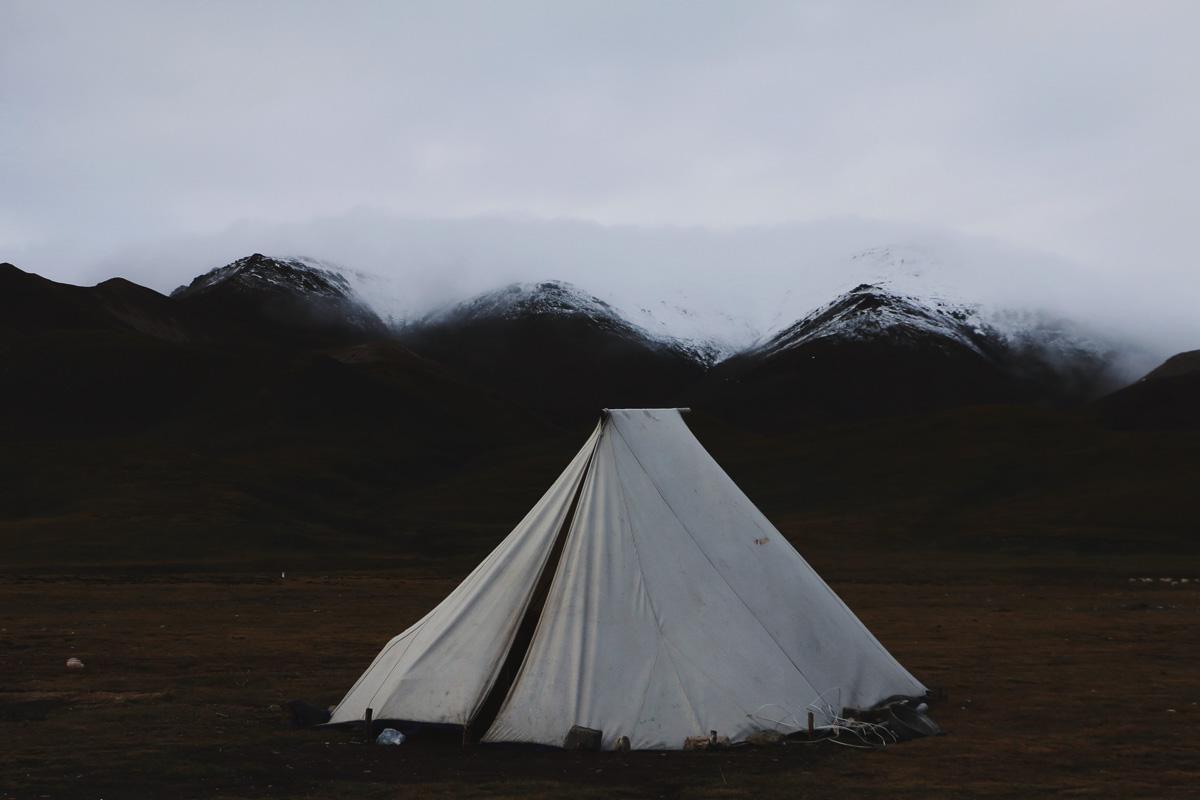 a 12 man teepee tent on a field in front of snowy mountains