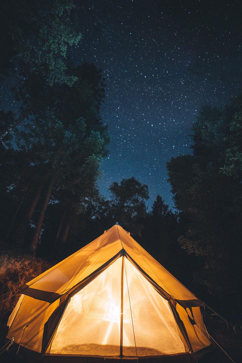 a four person canvas tent lit up from the inside at night