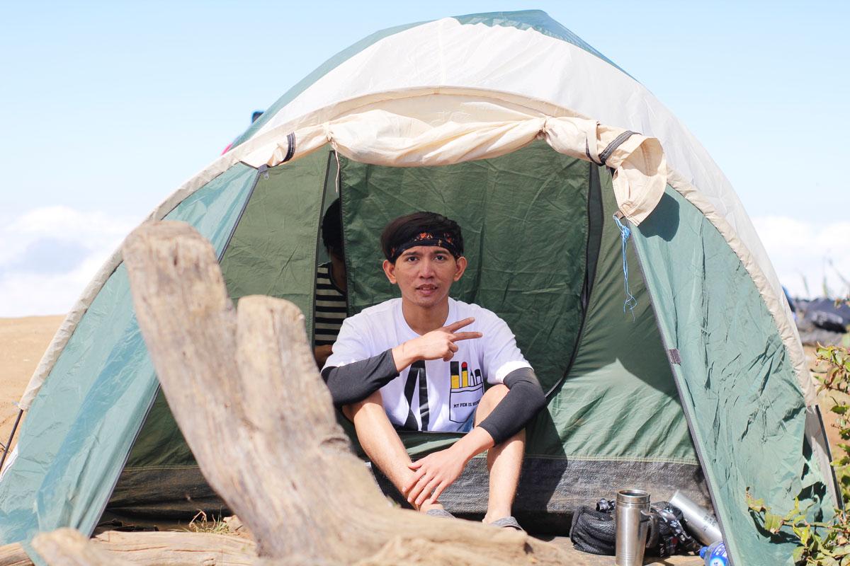 asian man sitting inside his 4 person tent with screen room
