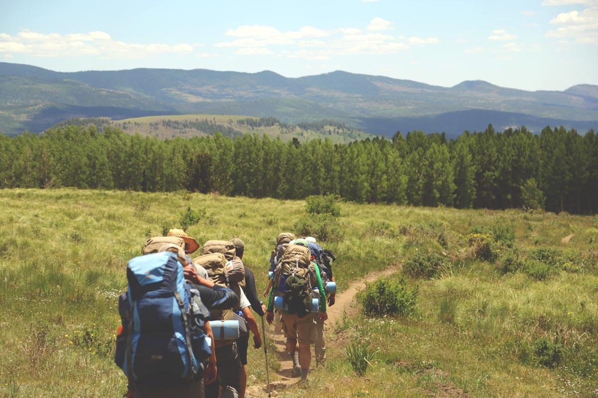 backpackers hiking in the fields and carrying their 4 man backpacking tents