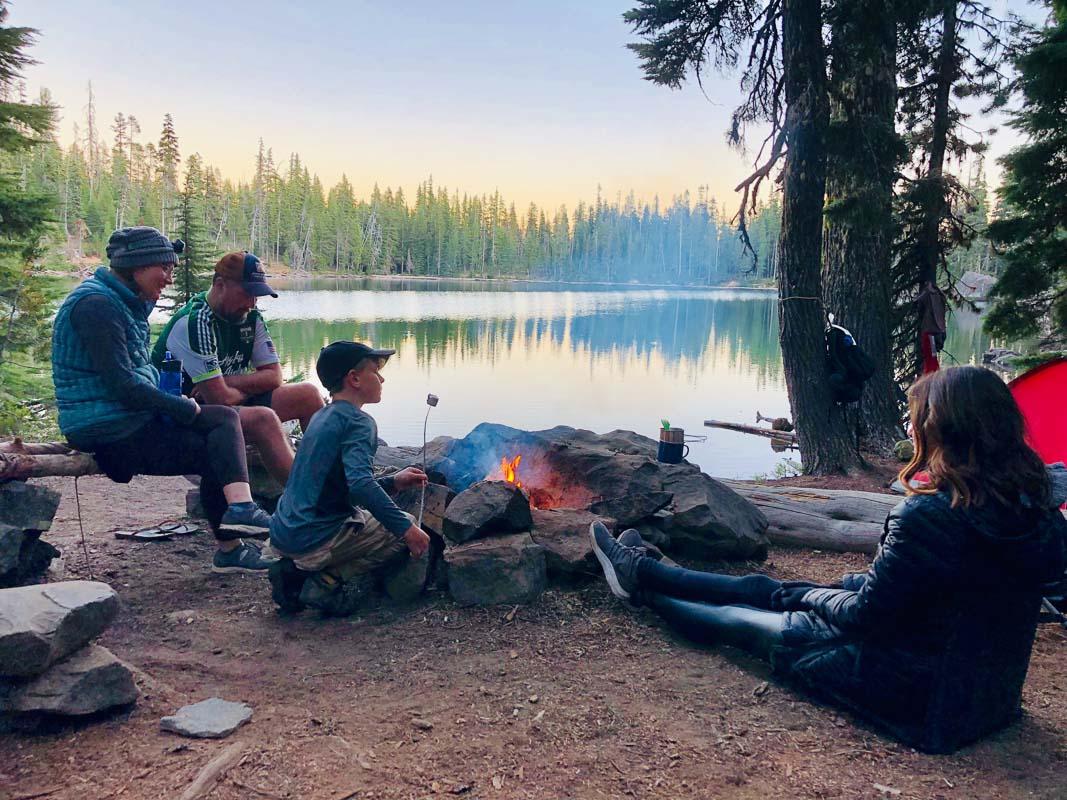 family of 4 sitting by the campfire after camping in their best 4 person camping tent