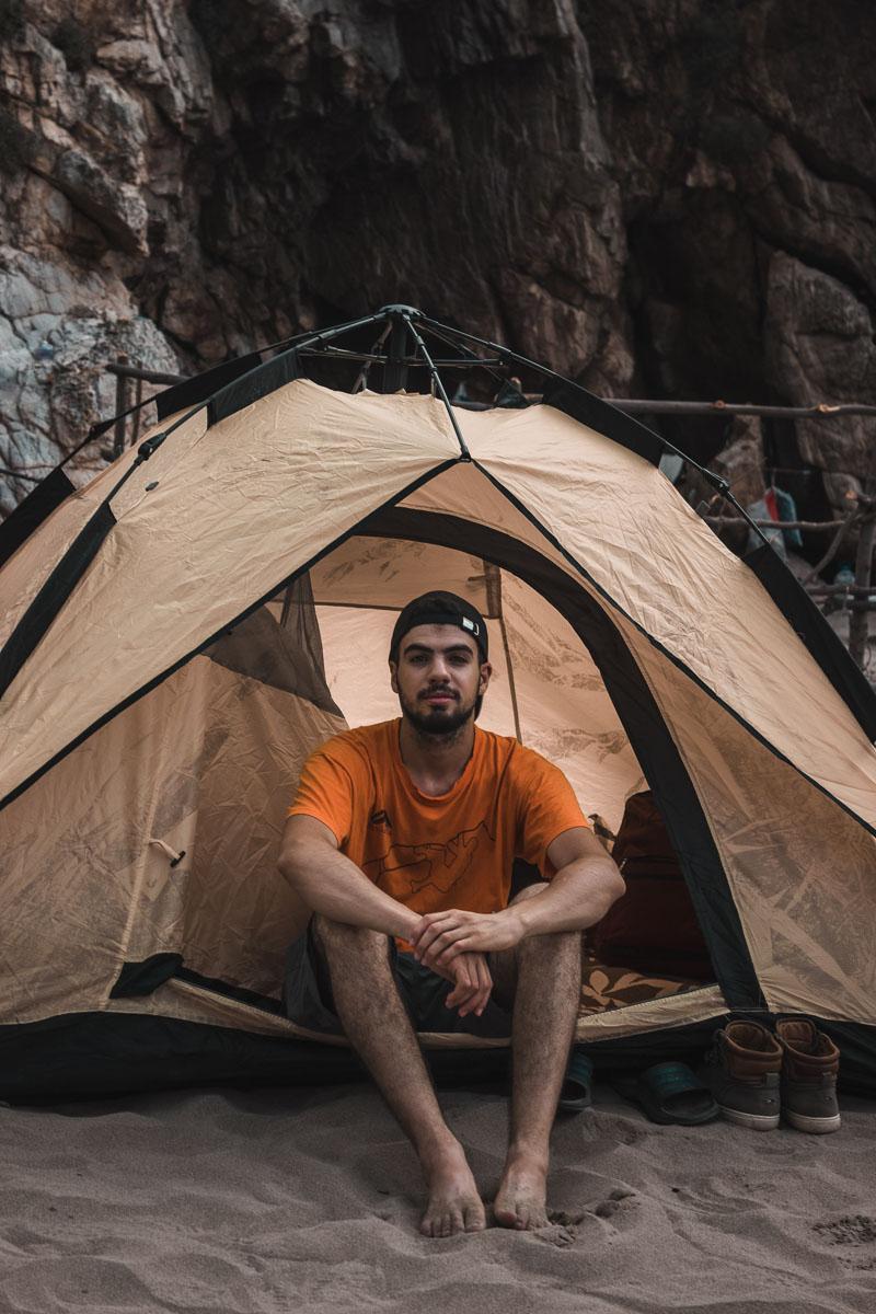 man in an orange shirt sitting in his 4 person instant tent