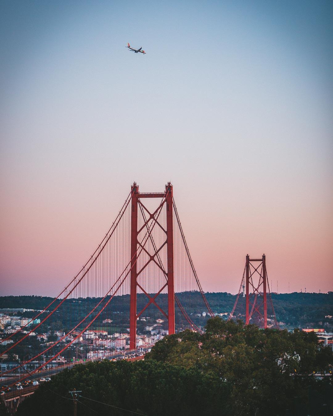 plane flying over the ponte 25 de abril