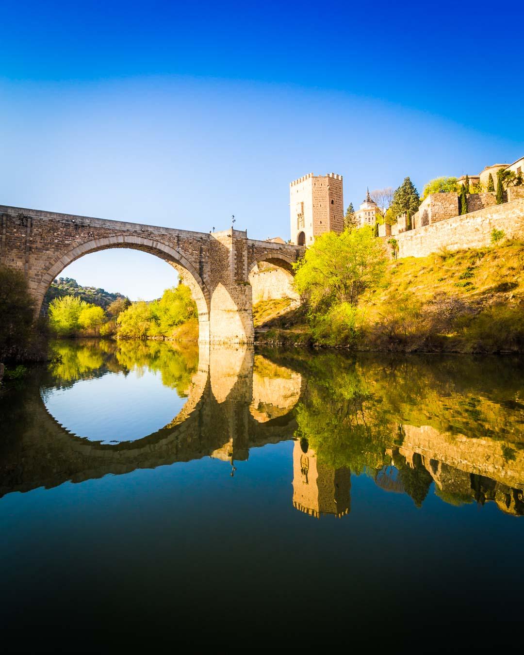 seeing the puente de alcantara reflecting in the tagus river, one of the top things to do in toledo spain