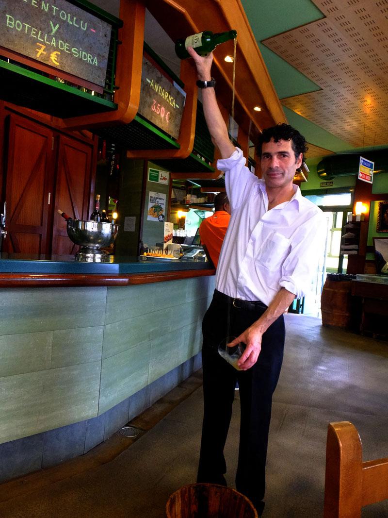 local man pouring sidra cider in asturias